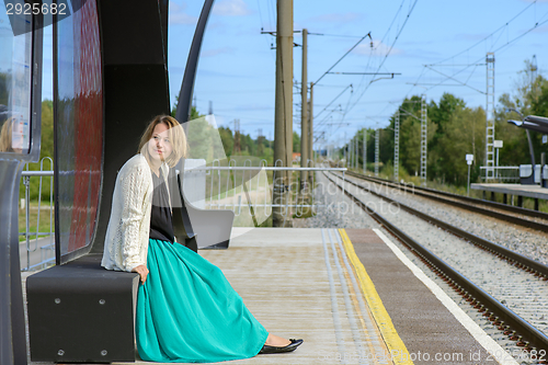 Image of Young girl sitting on the railway station