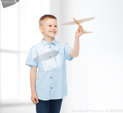 Image of smiling little boy holding a wooden airplane model