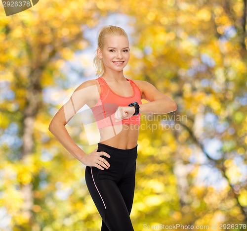 Image of smiling woman with heart rate monitor on hand