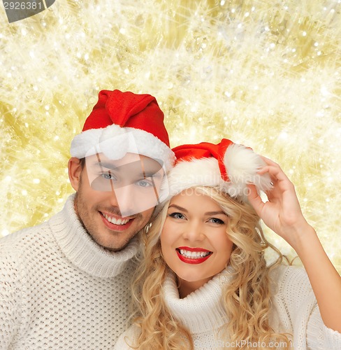 Image of smiling couple in sweaters and santa helper hats