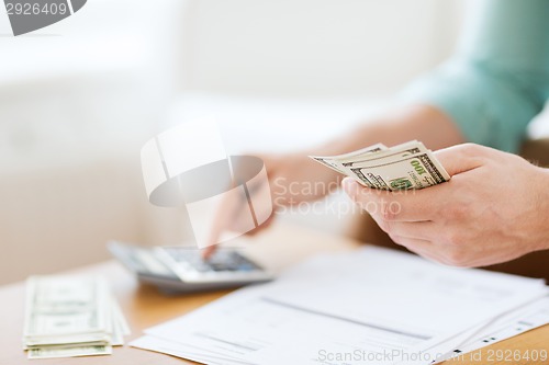 Image of close up of man counting money and making notes