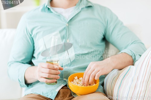 Image of close up of man with popcorn and beer at home