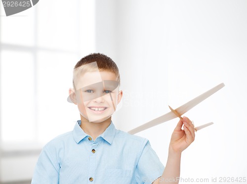 Image of smiling little boy holding a wooden airplane model