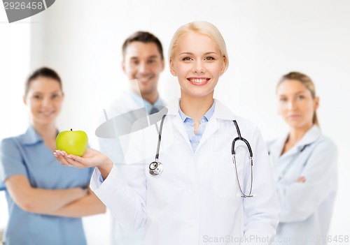 Image of smiling female doctor with green apple