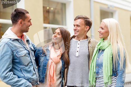 Image of group of smiling friends walking in the city