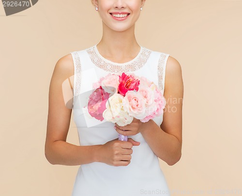 Image of smiling woman in white dress with bouquet of roses