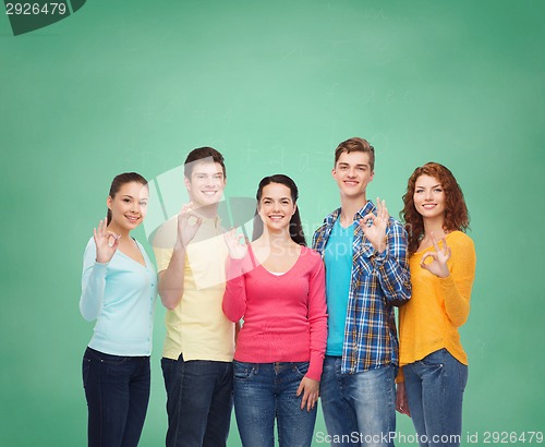 Image of group of smiling teenagers over green board