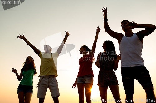 Image of smiling friends dancing on summer beach