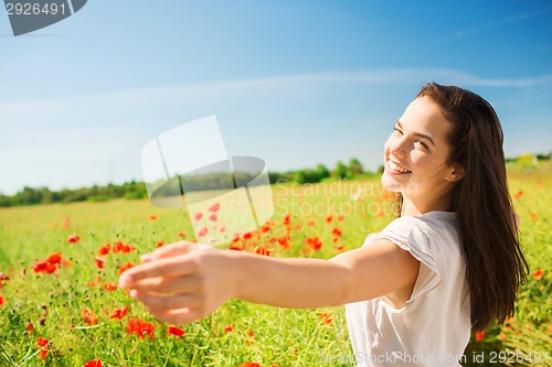 Image of smiling young woman on poppy field