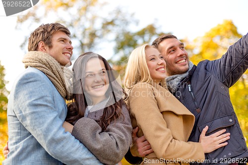 Image of group of smiling men and women in autumn park