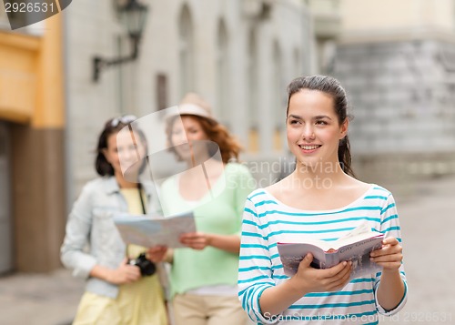 Image of smiling teenage girls with city guides and camera