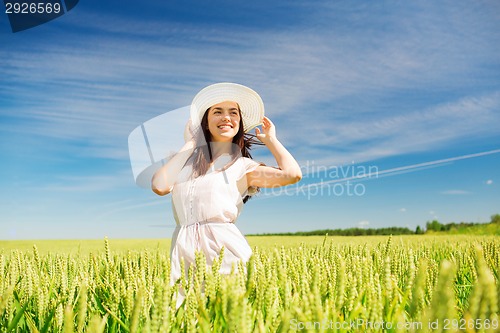 Image of smiling young woman in straw hat on cereal field