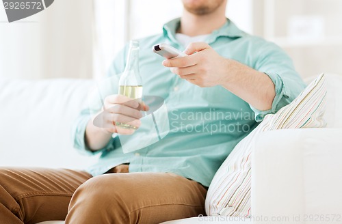 Image of man with beer and remote control at home