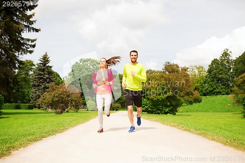 Image of smiling couple running outdoors