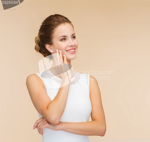 Image of smiling woman in white dress with diamond ring