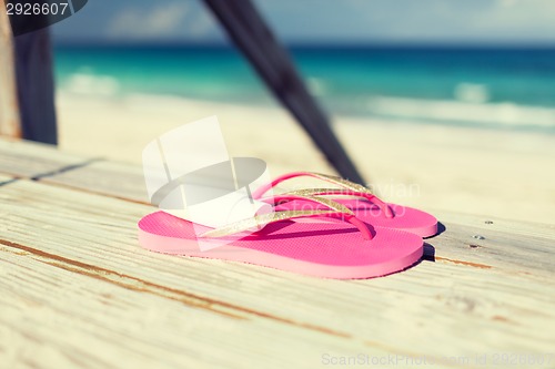 Image of close up of sunscreen and slippers at seaside