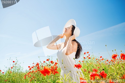 Image of smiling young woman in straw hat on poppy field