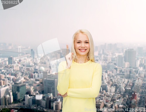 Image of smiling woman pointing her finger up