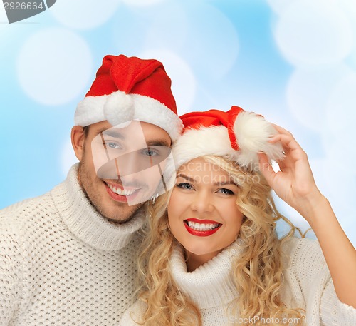 Image of smiling couple in sweaters and santa helper hats