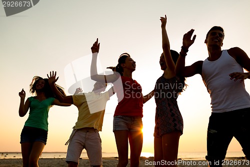 Image of smiling friends dancing on summer beach