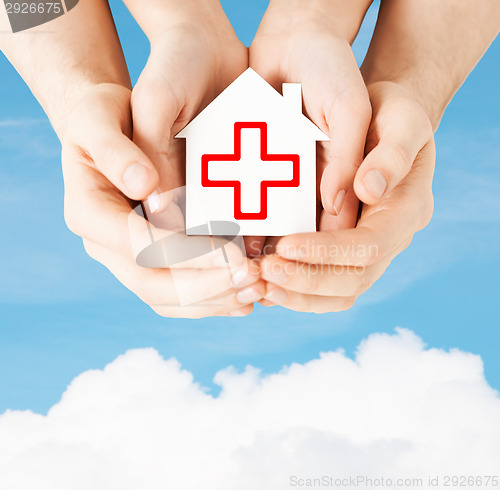 Image of hands holding paper house with red cross