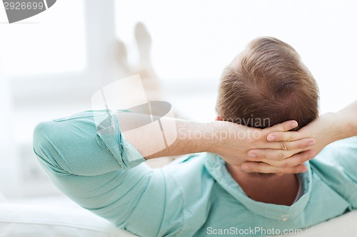 Image of man lying or sitting on sofa at home from back