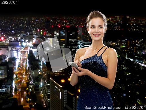 Image of smiling woman in evening dress with smartphone