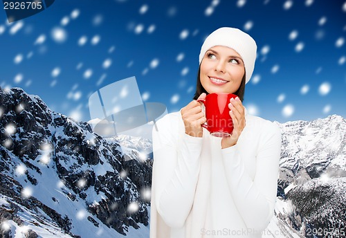 Image of smiling young woman in winter clothes with cup