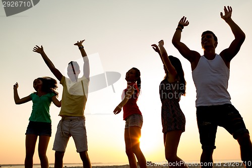 Image of smiling friends dancing on summer beach