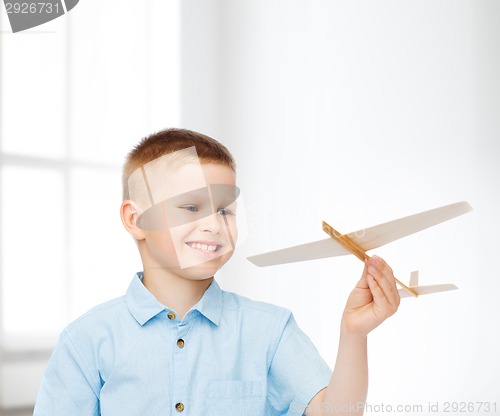 Image of smiling little boy holding a wooden airplane model