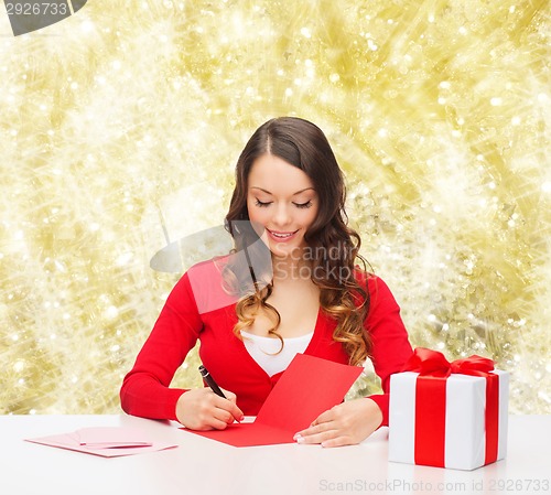 Image of smiling woman with gift box writing letter