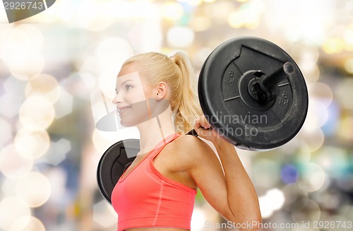 Image of smiling sporty woman exercising with barbell