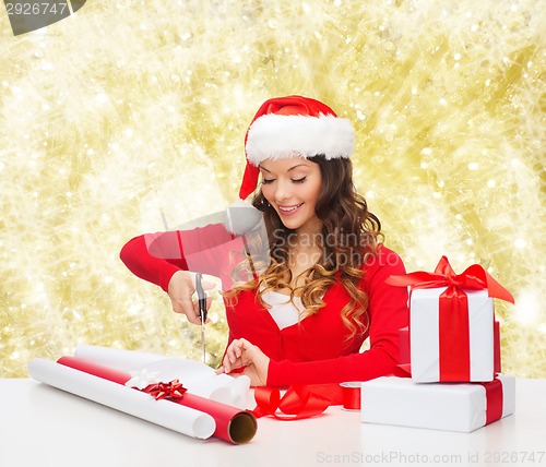 Image of smiling woman in santa helper hat packing gift box