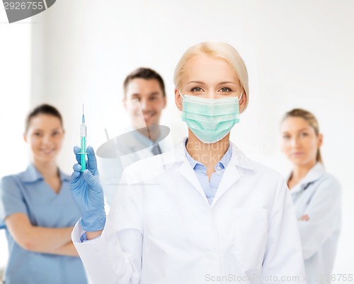 Image of doctor in mask holding syringe with injection