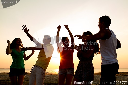 Image of smiling friends dancing on summer beach