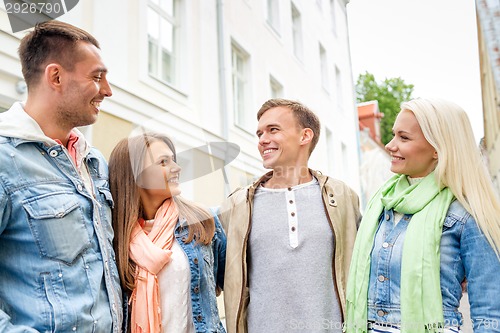 Image of group of smiling friends walking in the city