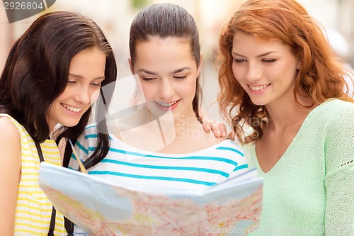 Image of smiling teenage girls with map and camera