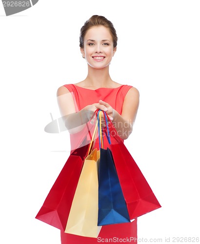 Image of smiling elegant woman in dress with shopping bags