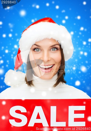 Image of smiling woman in santa helper hat with sale sign