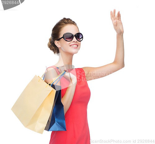 Image of smiling elegant woman in dress with shopping bags