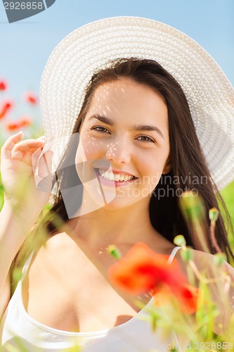 Image of smiling young woman in straw hat on poppy field