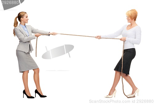 Image of two smiling businesswomen pulling rope