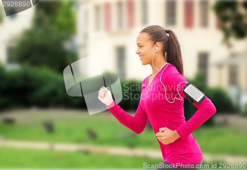 Image of smiling young woman running outdoors