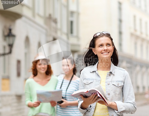 Image of smiling teenage girls with city guides and camera