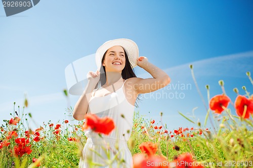 Image of smiling young woman in straw hat on poppy field