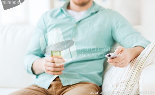 Image of man with beer and remote control at home