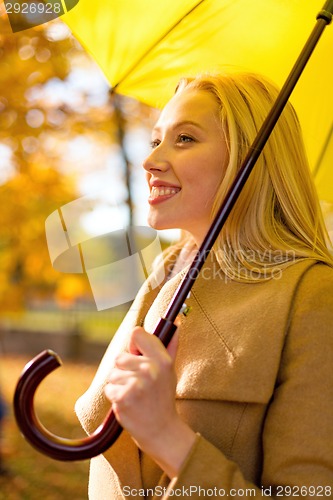 Image of smiling woman with umbrella in autumn park