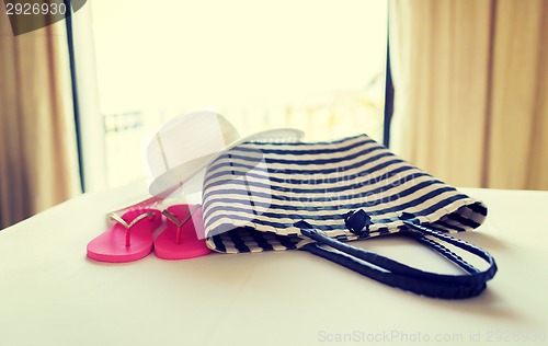 Image of close-up of beach bag, hat and flip-flop on bed