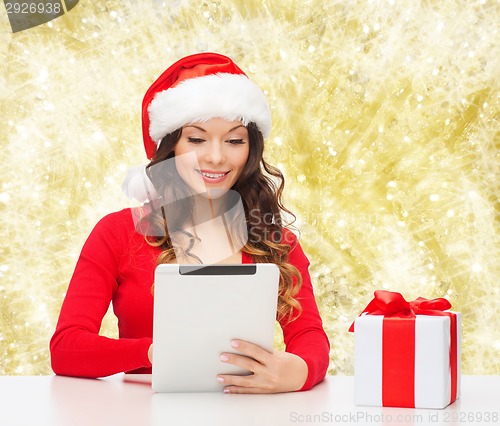 Image of smiling woman in santa hat with gift and tablet pc
