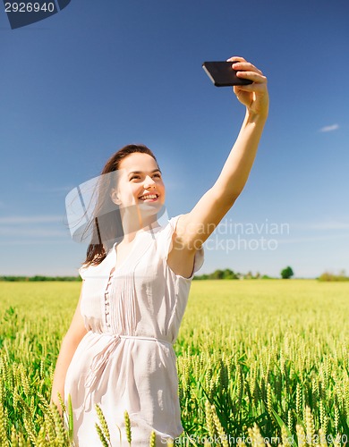 Image of smiling girl with smartphone on cereal field